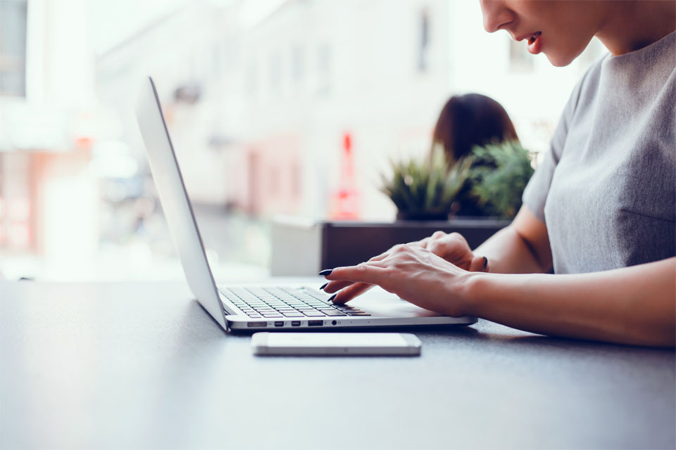 Woman Using Laptop in Cafe