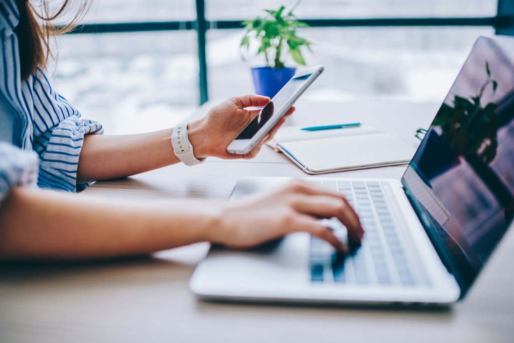 Woman using phone and laptop