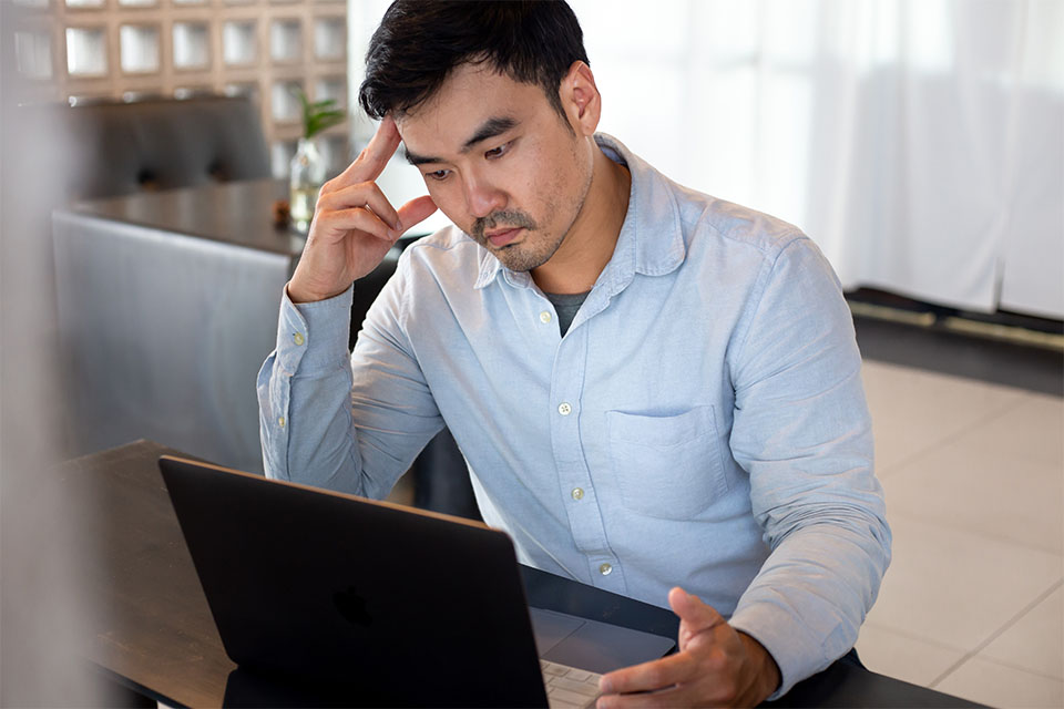 Asian Man Thinking in Front of Computer