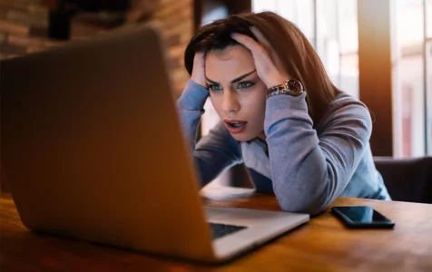 Frustrated Young Woman Looking at Laptop