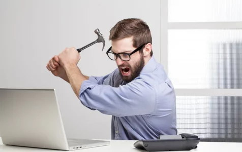 Man with Hammer in Front of Computer