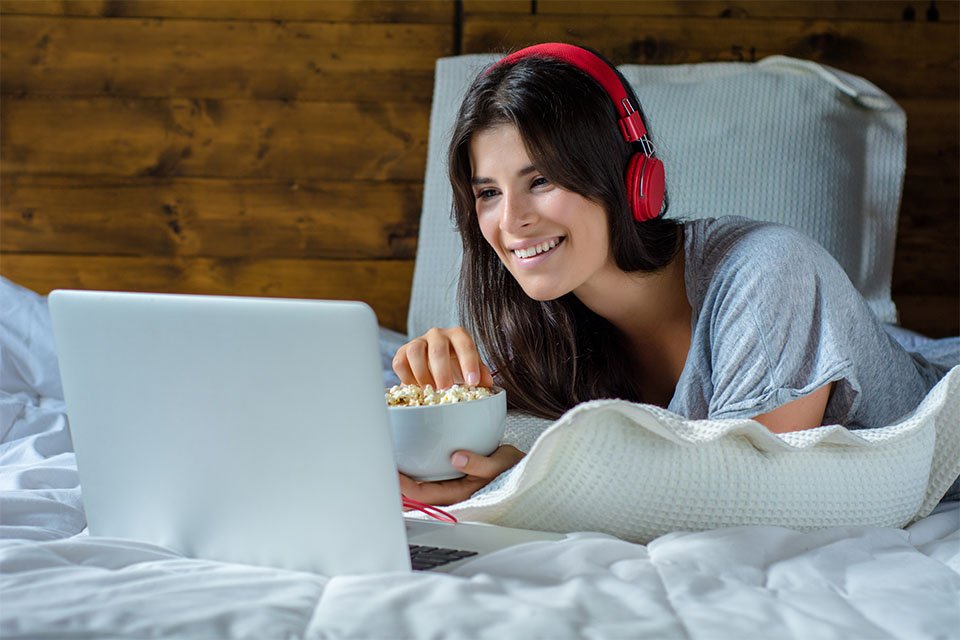 Smiling Girl with Headset and Popcorn Watching Movie